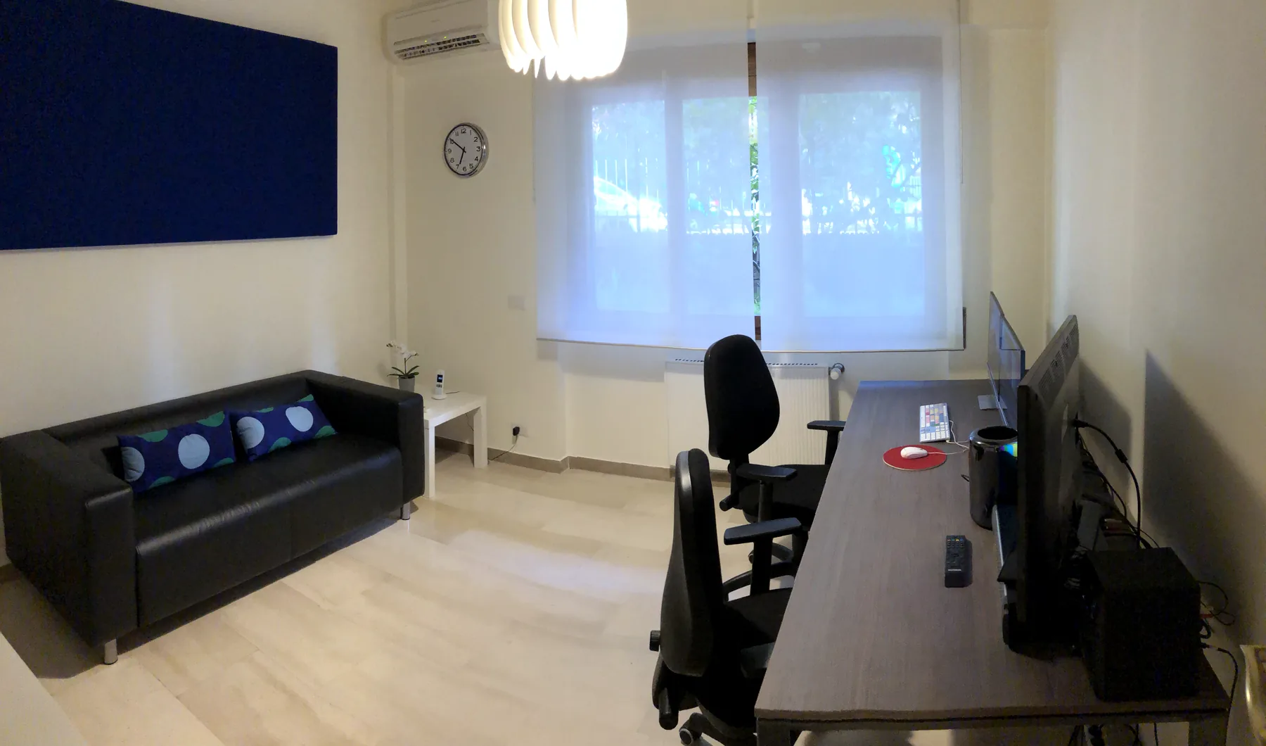 Una sala montaggio a noleggio vista per intero, con divano, finestra e pannello acustico
