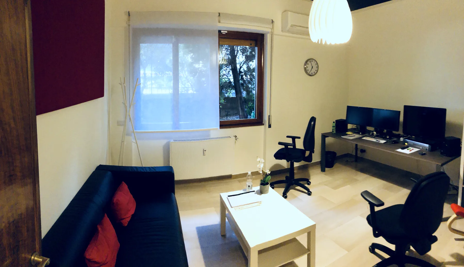 Sala montaggio a noleggio con pannello acustico rosso, divano e scrivania attrezzata
