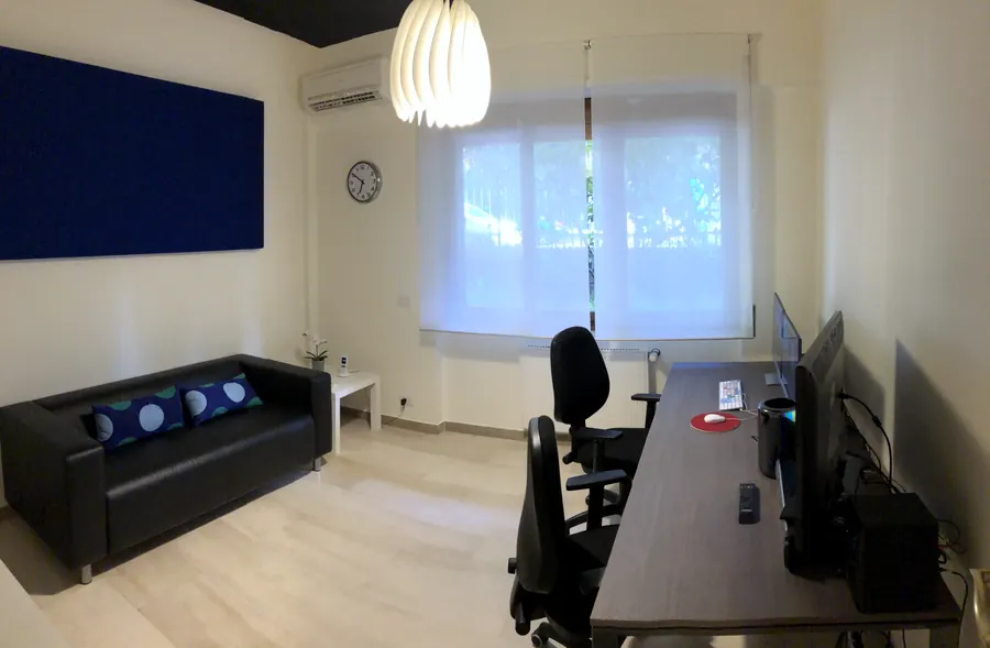 Una sala montaggio a noleggio vista per intero, con divano e pannello acustico
