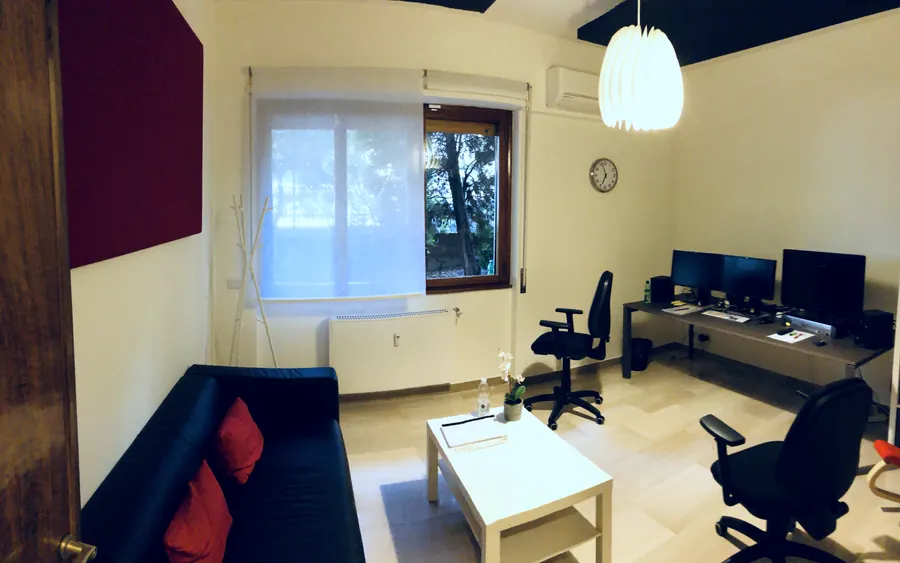 Sala a noleggio con pannello acustico rosso, divano e scrivania