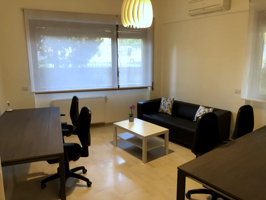 Sala a noleggio luminosa, con due scrivanie e un divano