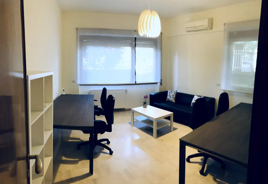 Sala a noleggio con scaffalatura, scrivania e divano